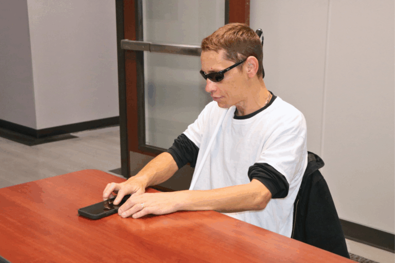 Ken, a client, on his phone during an adaptive technology training session.
