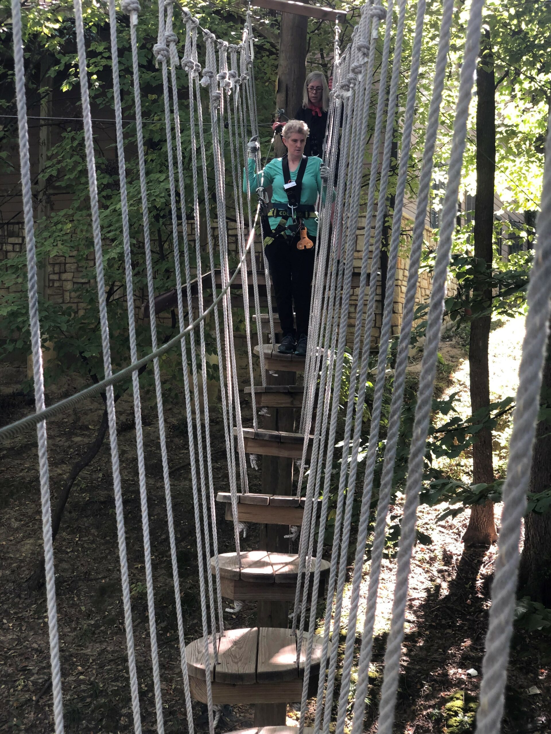 A cascading staircase made of long skinny pieces of wood that is susupended in air. A blind woman is making her way down them.