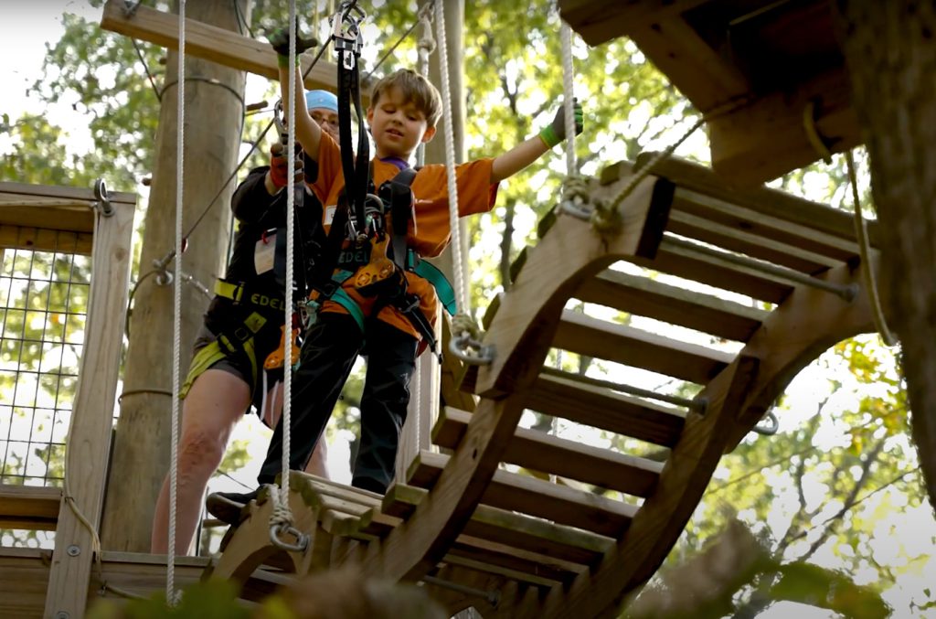 A young boy walks across a bridge at Tree Rush