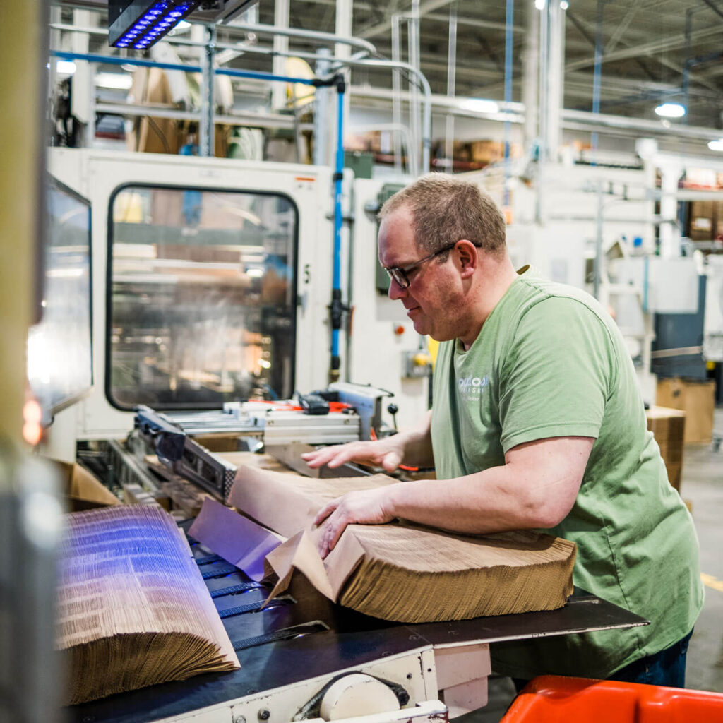 A man in a green shirt gathers natural paper towels into a bundle