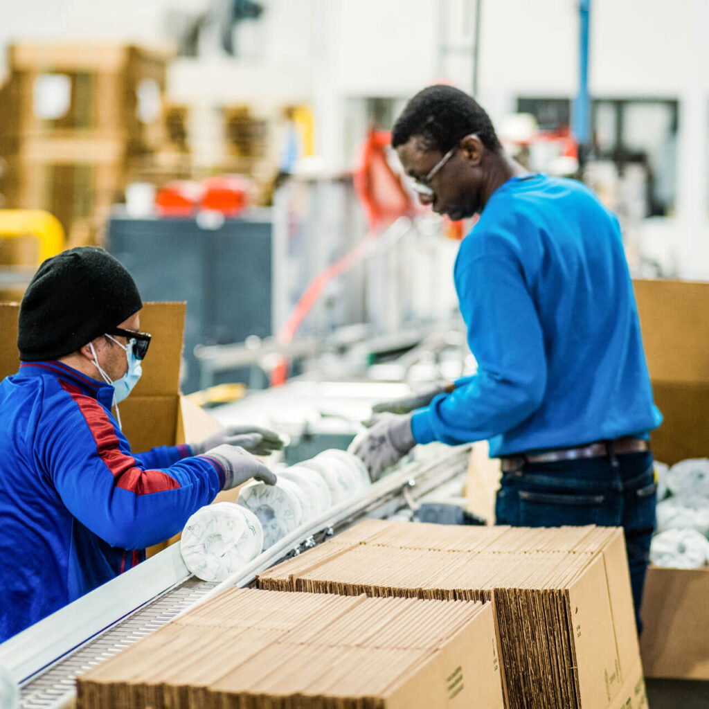 Two men move toilet paper on the production line