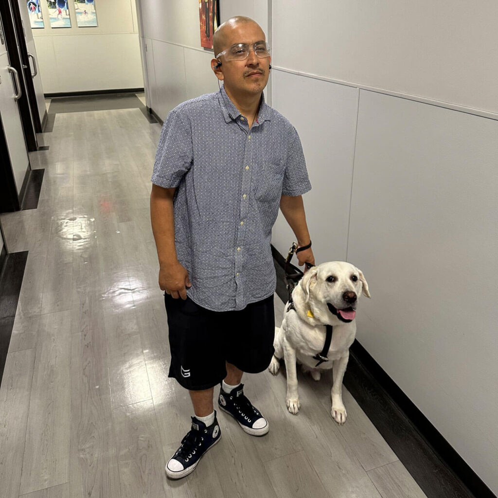 A man stands with his guide dog in the Outlook offices