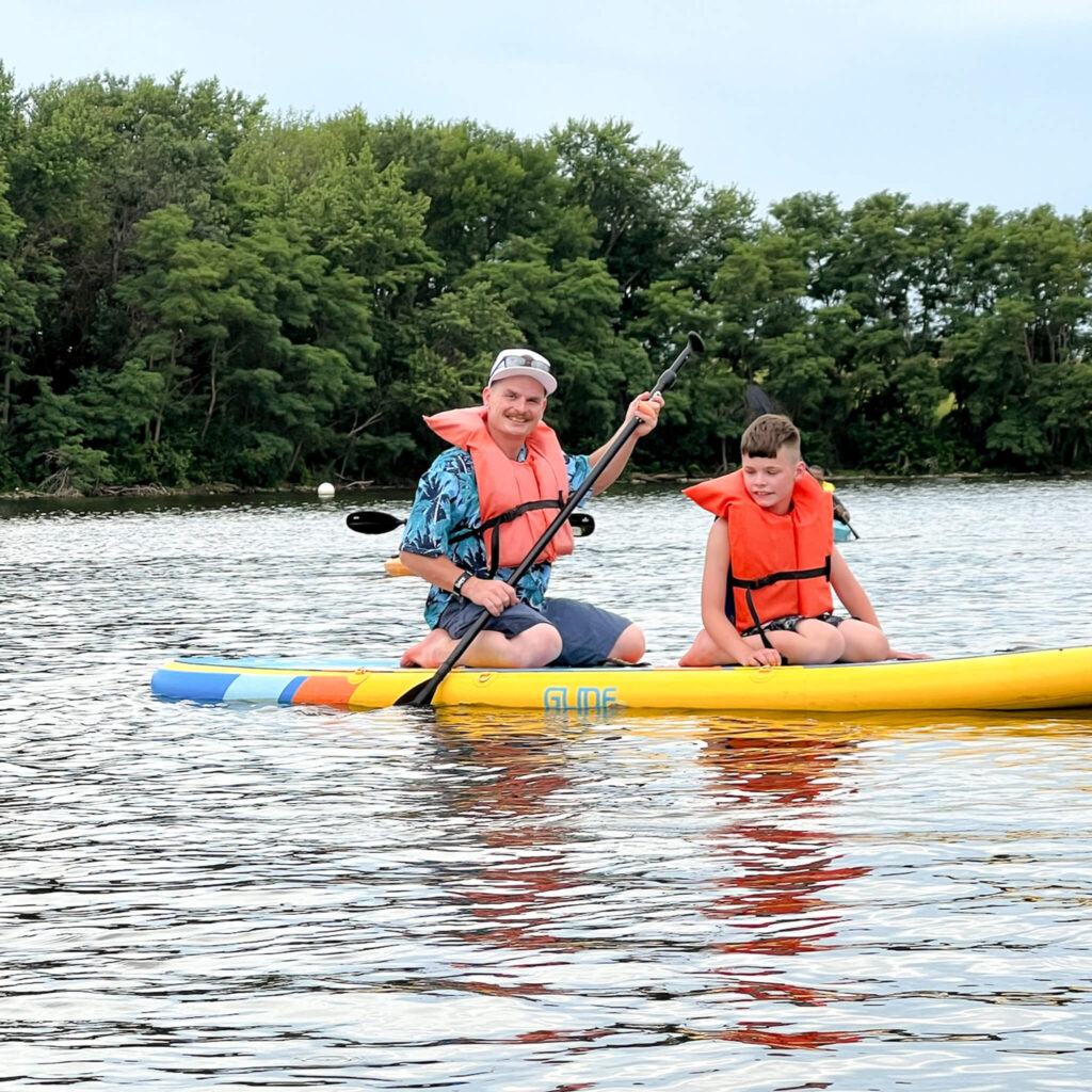 Young boy and father paddleboarding on a lake