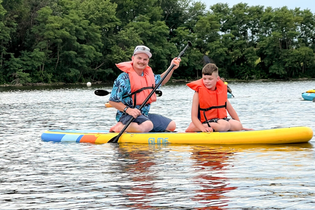 Young boy and father paddleboarding on a lake