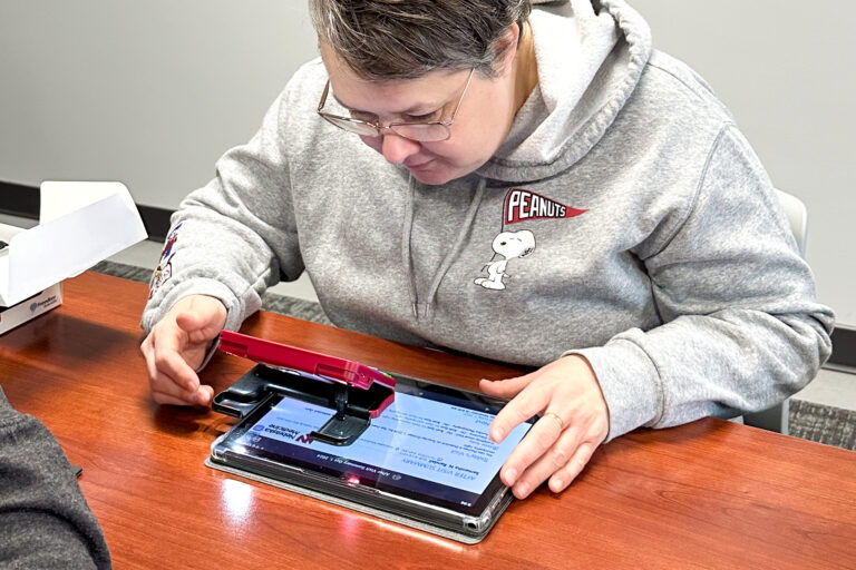 Visually impaired woman using adaptive technology on a phone and ipad