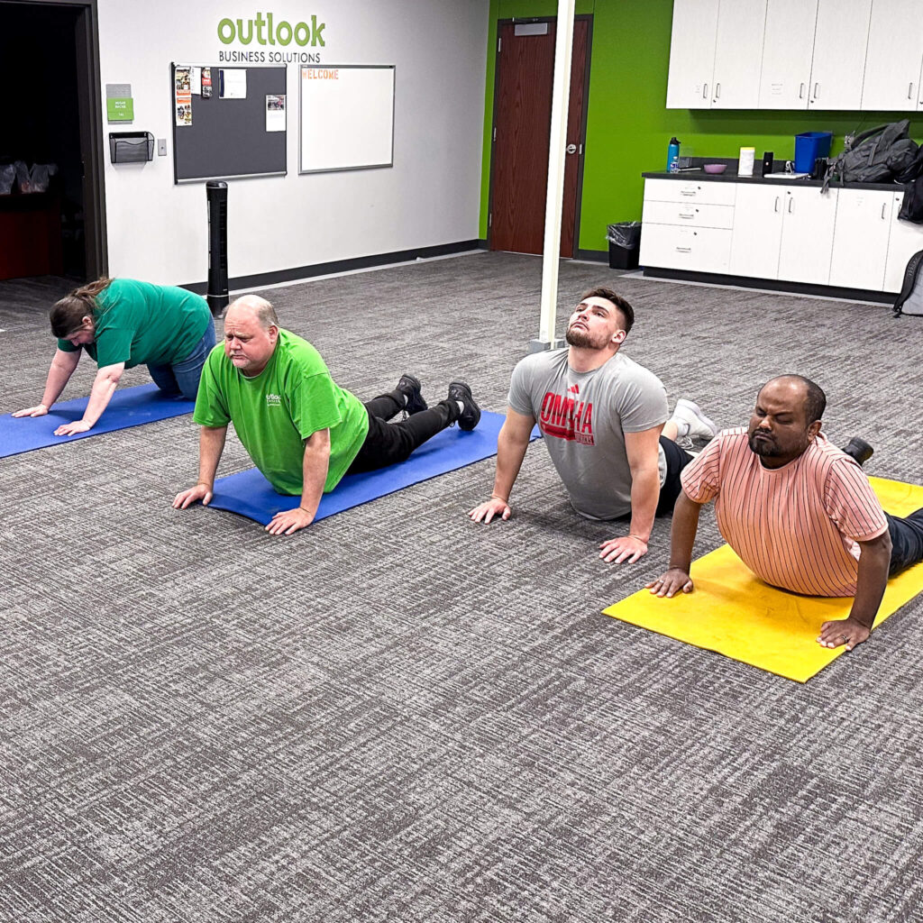 A group of four individuals working out on yoga mats, shown here in cobra pose.