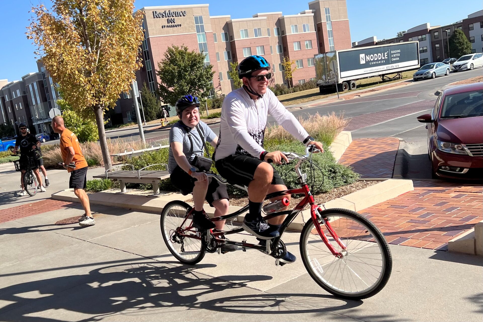 two people riding on a tandem bike wearing helmets
