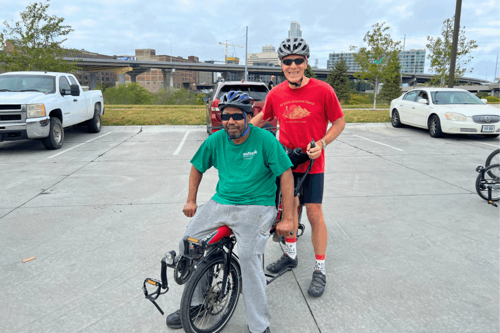 Photo of a male volunteer bike captain and a male rider on a tandem bike.