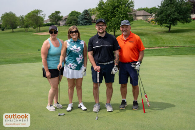 2 women and 2 men smiling on the course.
