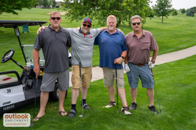 4 men smliing on the course.