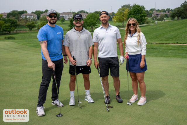 3 men and one woman smiling on the course.