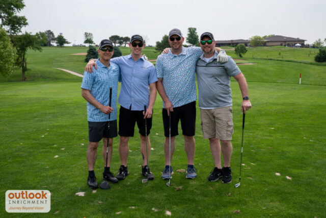 4 men smiling on the course.