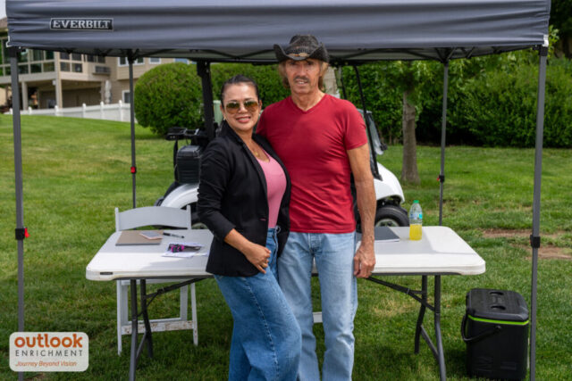 Man and woman smiling at a sponsor hole.