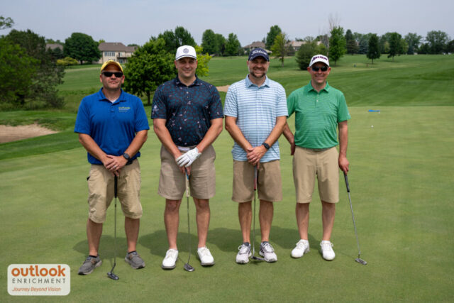 4 men smiling on the course.