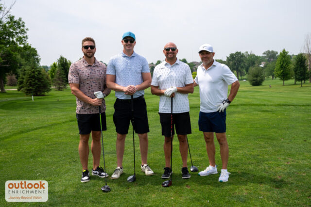 4 men smiling on the course.