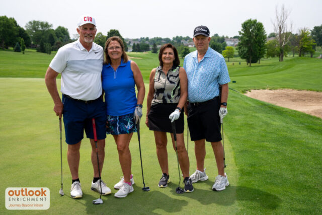 2 men and 2 women smiling on the course.