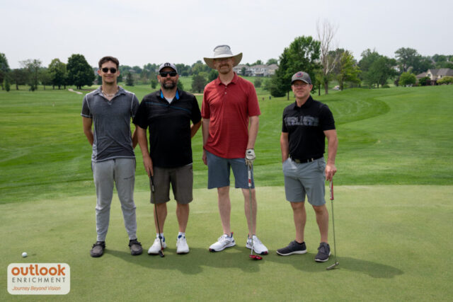 4 men smiling on the course.
