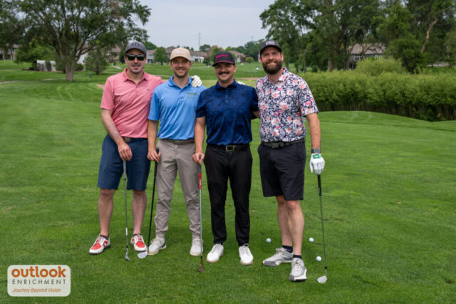 4 men smiling on the course.