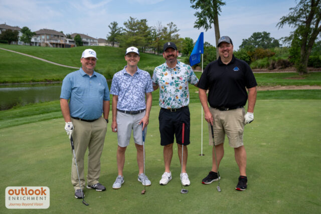 4 men smiling on the course.
