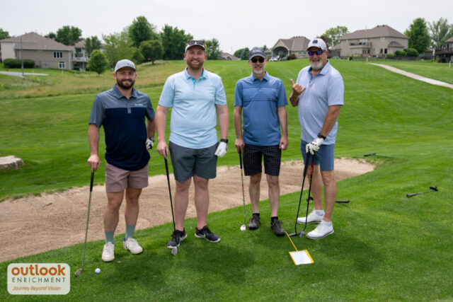 4 men smiling on the course.