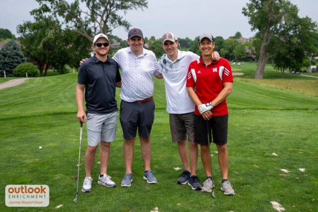 4 men smiling on the course.