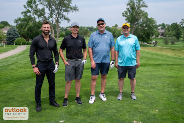 4 men smiling on the course.
