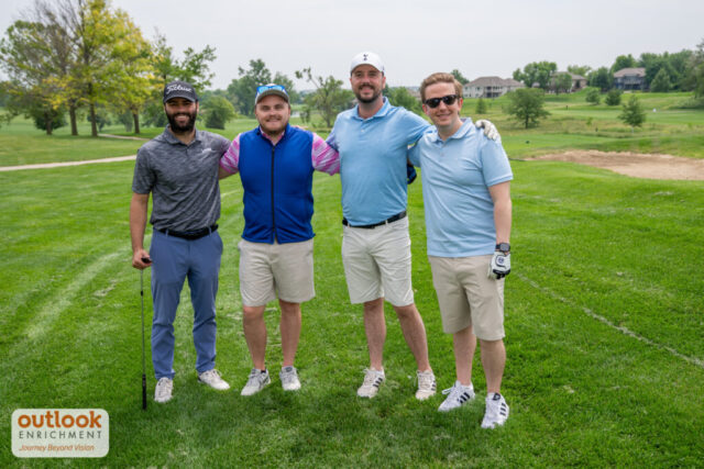 4 men smiling on the course.