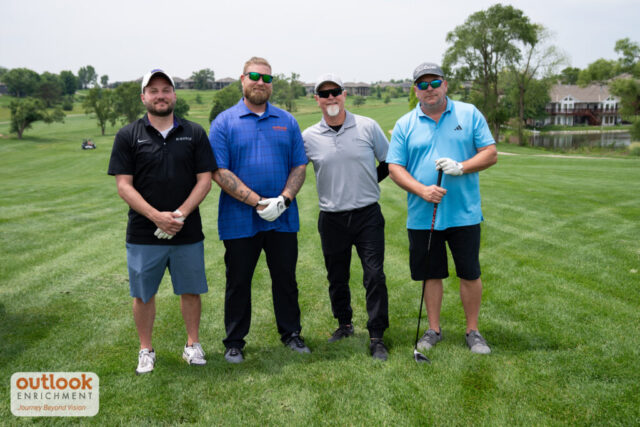 4 men smiling on the course.