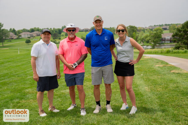 1 woman and 3 men smiling on the course.