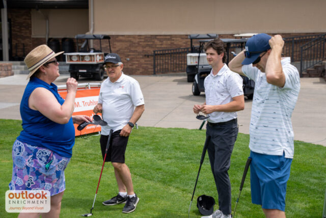 Group of men learning the instructions for a hole game from a woman volunteer.