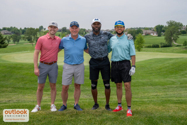 4 men smiling on the course.