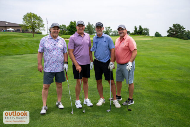 4 men smiling on the course.