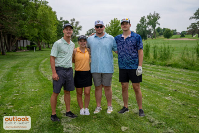 1 woman and 3 men smiling on the course.