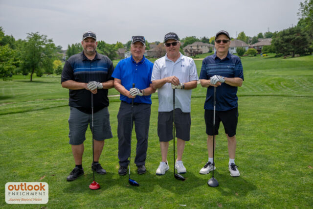 4 men smiling on the course.