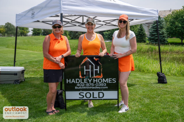 Hadley Homes sponsor hole. 3 ladies standing in front of a "sold" sign.