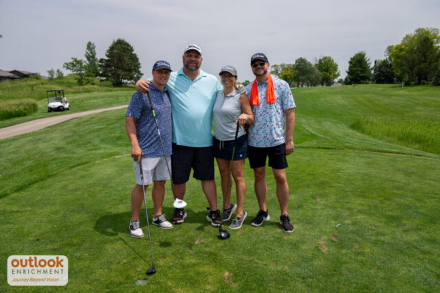 1 woman and 3 men smiling on the course.