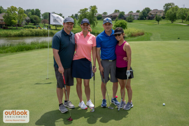 2 women and 2 men smiling on the course.