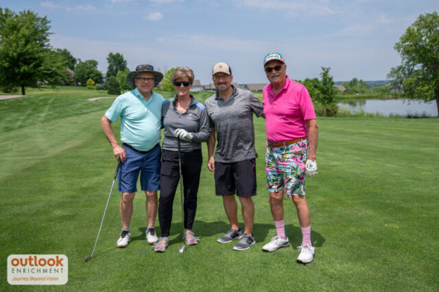 1 woman and 3 men smiling on the course.