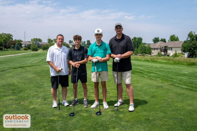 4 men smiling on the course.