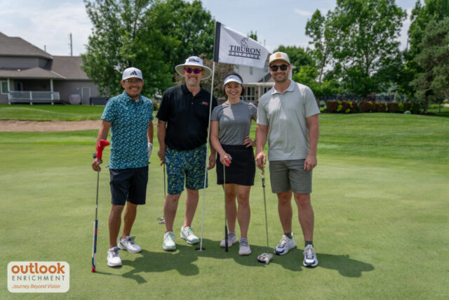 3 men and 1 woman smiling on the course.