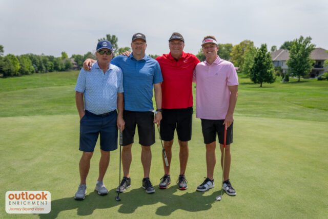 4 men smiling on the course.