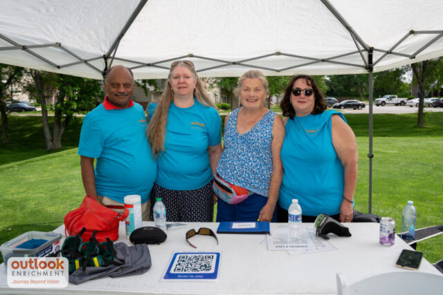 Volunteers smiling at their tent. 3 women and 1 man.