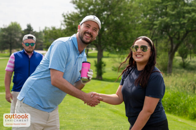 A man and a woman shaking hands and smiling for a photo.