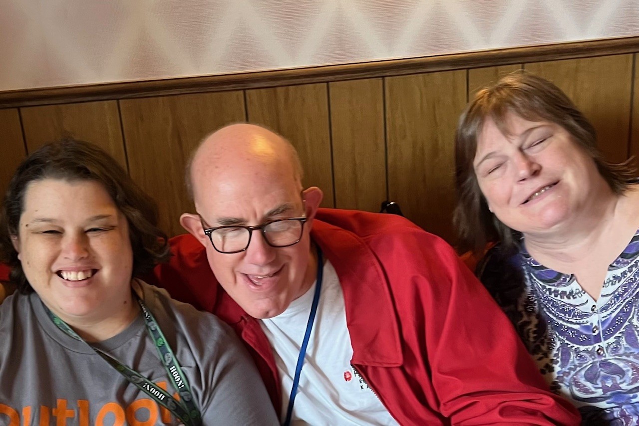 Amber, Jim and Cheri sitting in a booth at a restaurant during a past white cane day celebration.