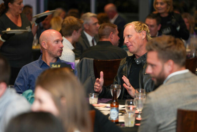 Two men at a table chatting.