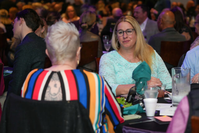 Two woman are engaged in a conversation at their table.