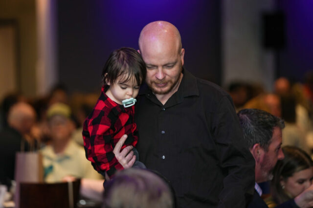 A man is standing and holding a child.