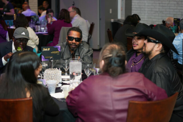 Outlook associates Willie, Alex, and Koffi at a table with Willie's guests.