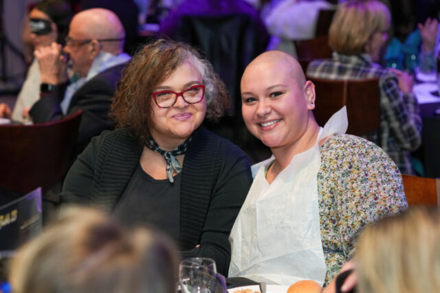 Two women smiling for a photo, one is wearing a bib.