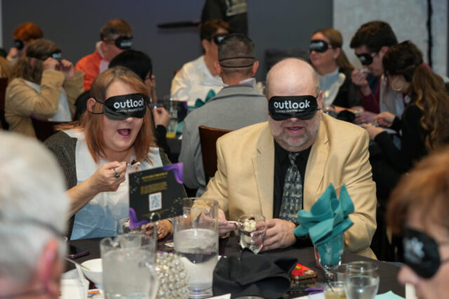 A man and woman are wearing sleep shades and enjoying their dessert.